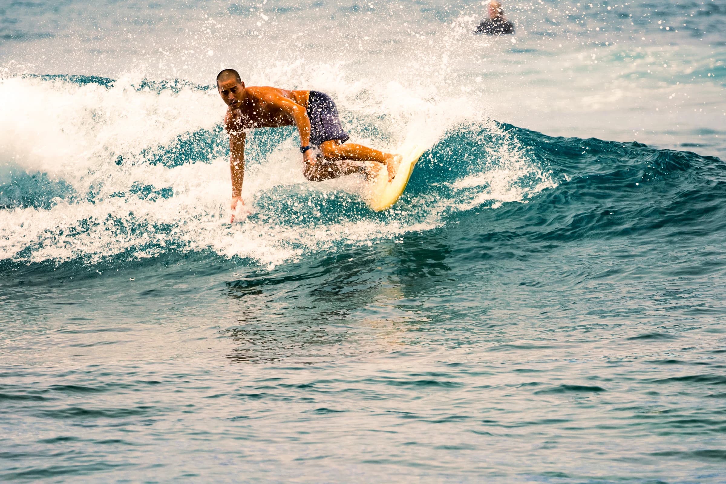 Surfer riding a yellow board through whitewater